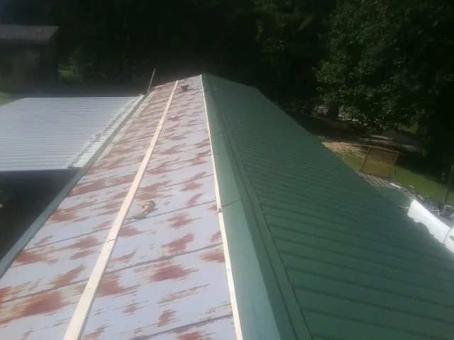 Old rusted panels beside newly installed green metal roofing — Wind Damage Roof Repair by Roofing Brothers in Shirley