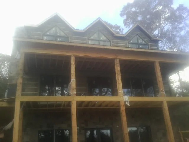 Dormers and porch framing on a large log home under construction — Roof Coating work by our crew in Shirley
