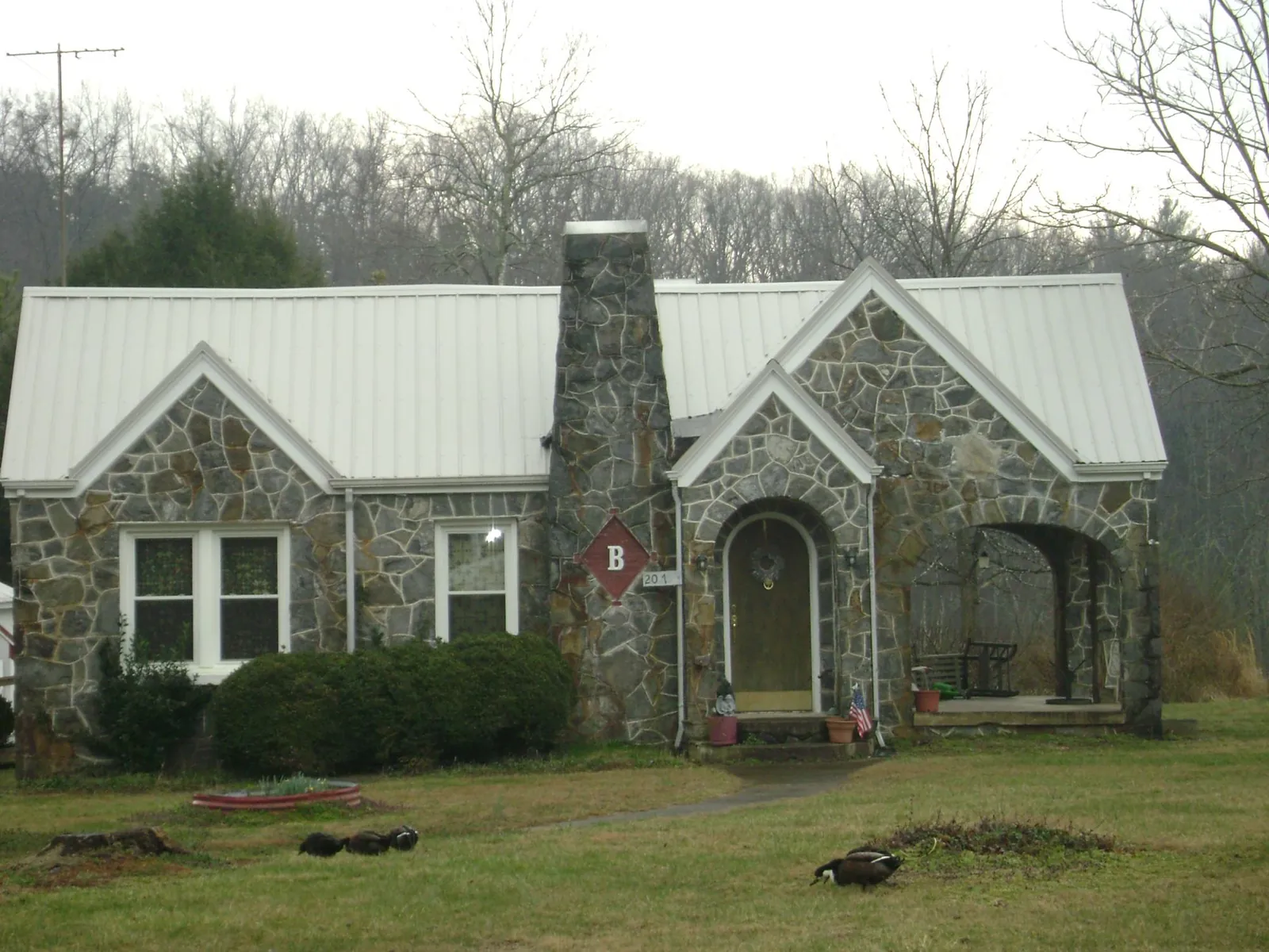 White metal roof on a stone cottage with steep gables in Shirley
